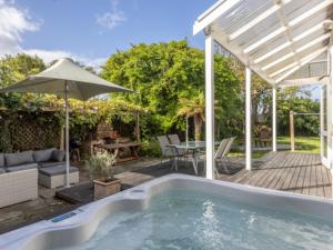 a backyard with a pool and a table and an umbrella at Beautiful villa in Napier with spa in Napier