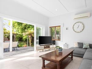 a living room with a couch and a clock on the wall at Beautiful villa in Napier with spa in Napier