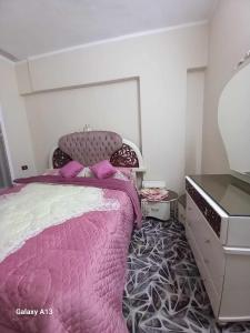 a bedroom with a pink bed and a dresser at شقة سكنية in Shibīn al Kawm
