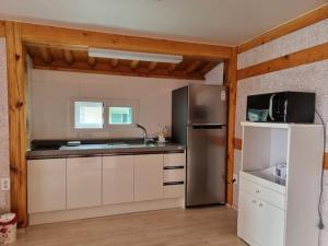 a kitchen with a stainless steel refrigerator and white cabinets at Museon Hanok Stay Jebi in Haenam