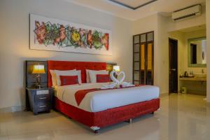 a bedroom with a large bed with a red headboard at Vamana Resort - CHSE Certified in Gili Trawangan