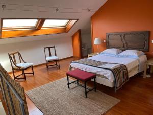 a bedroom with a large bed and two chairs at Studio Azul in São João da Ribeira