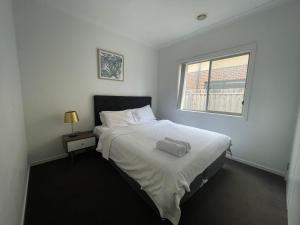a bedroom with a white bed and a window at Discover Luxury Living & Aviation History in Point Cook
