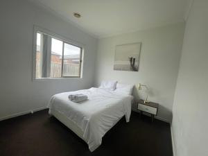 a white bedroom with a bed and a window at Discover Luxury Living & Aviation History in Point Cook