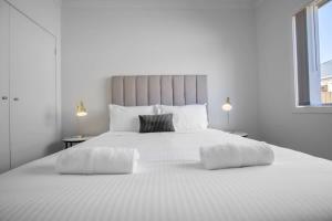 a large white bed with two tables and two lamps at Discover Luxury Living & Aviation History in Point Cook