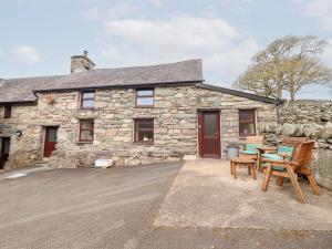 a stone house with a table and chairs in front of it at Y Bwthyn in Llanbedr