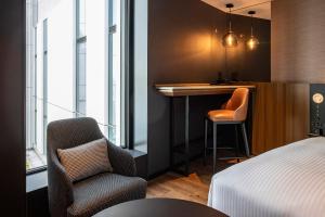 东京Hotel Metropolitan Tokyo Haneda的酒店客房,设有床、酒吧和椅子