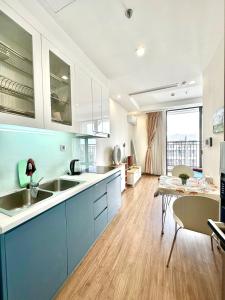 eine große Küche mit blauen Schränken und einem Tisch in der Unterkunft Top Floor High Quality Studio In Vinhomes Green Bay Near Marriott, Grand Plaza in Hanoi