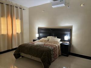 Un dormitorio con una cama y dos lámparas y una ventana. en Bella House, en Inhambane