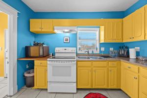 a kitchen with yellow cabinets and a white stove top oven at Cozy & Creative Top Unit in Lou's Arts District in Louisville