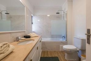a bathroom with a sink and a toilet and a tub at Salgados 1 Bedroom Apartment - 500m from the Beach in Guia +24 photos