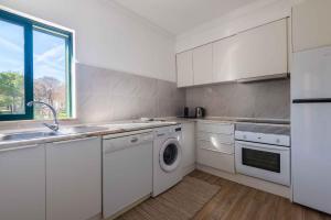 a white kitchen with a sink and a dishwasher at Salgados 1 Bedroom Apartment - 500m from the Beach in Guia
