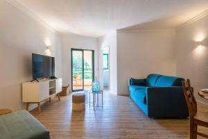 a living room with a blue couch and a tv at Salgados 1 Bedroom Apartment - 500m from the Beach in Guia