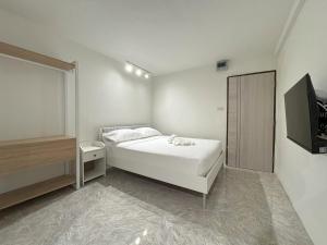 a white bedroom with a bed and a television at 95 Lodge in Bangkok