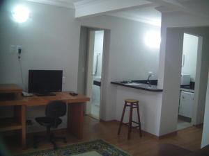 a room with a desk with a computer and a sink at Hotel Ampiezza in Curitiba