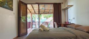a bedroom with a bed and a large window at Castaway Surf Retreat in Sekongkang