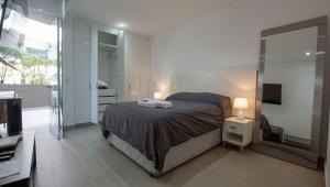 a bedroom with a bed and a tv and a mirror at Condominio Ocean reef in San Bartolo