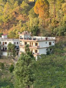a building on the side of a hill with trees at Doctor Kush Stay Cafe Music in Rāmgarh