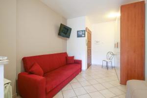 a living room with a red couch and a television at Il Nido nel Verde - Fiumicino Airport - Self Check-In in Fiumicino
