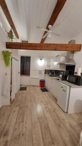 a large kitchen with white cabinets and a wooden floor at Belle vue in Agde