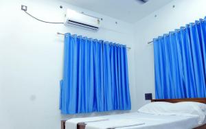 AlleppeySreeragam Residency Cherthala的一间卧室配有蓝色窗帘和一张带白色床单的床