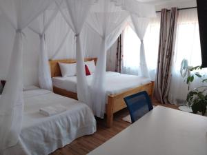 a bedroom with two beds and a blue chair at Annodas Homes Milimani Kisumu in Kisumu
