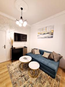 un salon avec un canapé bleu et deux tables dans l'établissement Apartman Agram, à Zagreb