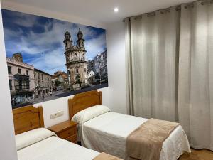 Un dormitorio con dos camas y una imagen de una torre. en Camiño Portugues, en Padrón