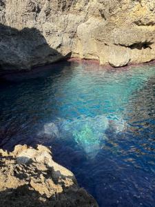 a body of water next to a rocky cliff at La Meridiana in Augusta