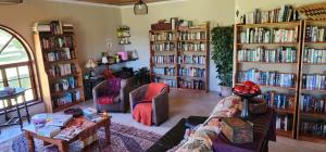 a living room filled with book shelves filled with books at Greystone Lodge in Dullstroom
