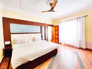 比姆塔尔A Premium Hotel Kavyansh Near Bypass Road - Hygiene & Spacious Room - BEST HOTEL IN BHIMTAL的一间带大床和吊扇的卧室