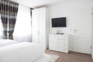 a white bedroom with a bed and a tv at Passat in Norddeich