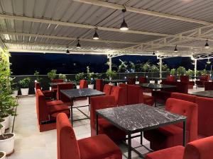 a restaurant with black tables and red chairs at Hotel Nikanshvee in Udaipur