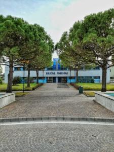 a park in front of a building with trees at Residenza delle Terme in Bibione