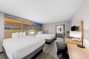a hotel room with two beds and a desk at Days Inn by Wyndham Gainesville in Gainesville