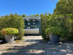 a garage with two potted plants in front of it at Luxe Houten Pod 3 Aagtekerke Dichtbij Zee en Natuur in Aagtekerke