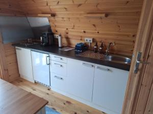 a kitchen with white cabinets and a sink and wooden walls at Luxe Houten Pod 3 Aagtekerke Dichtbij Zee en Natuur in Aagtekerke