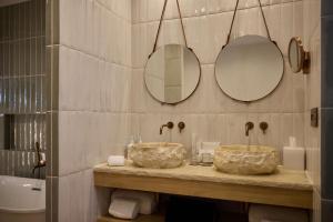 two sinks in a bathroom with two mirrors at Cala San Miguel Ibiza Resort, Adults only, Curio Collection by Hilton in Puerto de San Miguel