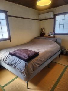a large bed in a room with two windows at HOSTEL KURIYA OSAKA in Izumi-Sano