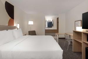 a hotel room with a large white bed and a desk at Spark By Hilton Santa Nella in Santa Nella