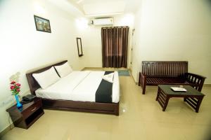 a bedroom with a bed and a couch and a table at Regal residency in Perintalmanna