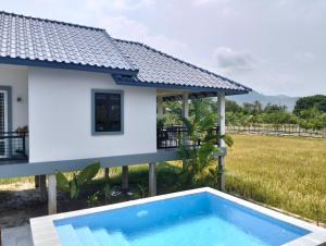 a villa with a swimming pool in front of a house at Baksaei Retreat Ricefield Villas in Kampot