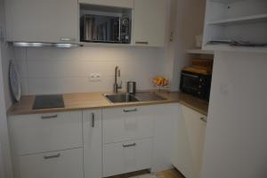 a kitchen with white cabinets and a sink at Le Bassin à vos pieds avec T2 Élégant entre Plage et Hyper Centre in Arcachon