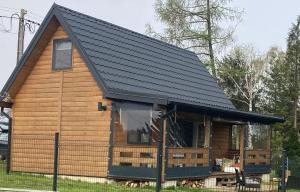 a log cabin with a black roof at Uroczy domek nad Gilem in Miłomłyn