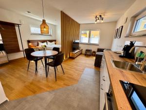 a kitchen and living room with a table and chairs at JUNIPRO Apartments Losheim in Losheim