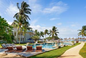 a resort pool with lounge chairs and palm trees at Heritage Le Telfair Golf & Wellness Resort in Bel Ombre