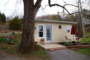 una casetta in un giardino con un albero di River Lane Cottage a Dunnville