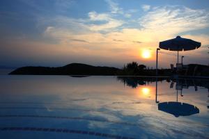 a swimming pool with an umbrella and the sunset at Elies Houses in Agnontas