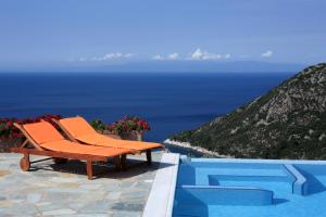 a pool with orange chairs and the view of the ocean at Elies Houses in Agnontas