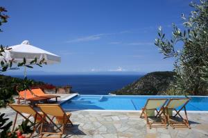 a group of chairs and an umbrella next to a swimming pool at Elies Houses in Agnontas